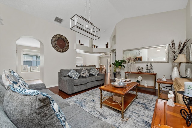 living area featuring arched walkways, visible vents, baseboards, and wood finished floors