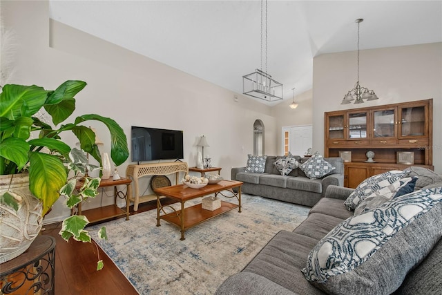 living area with wood finished floors, arched walkways, and high vaulted ceiling