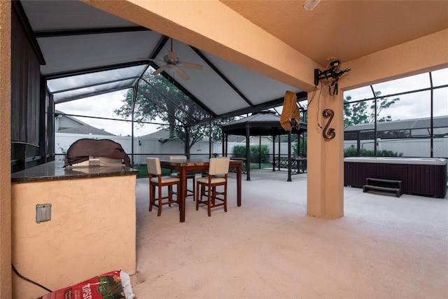 view of patio / terrace with a ceiling fan, a lanai, outdoor dining area, an outdoor kitchen, and a hot tub