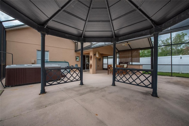 view of patio / terrace with glass enclosure, fence, central AC unit, and a hot tub