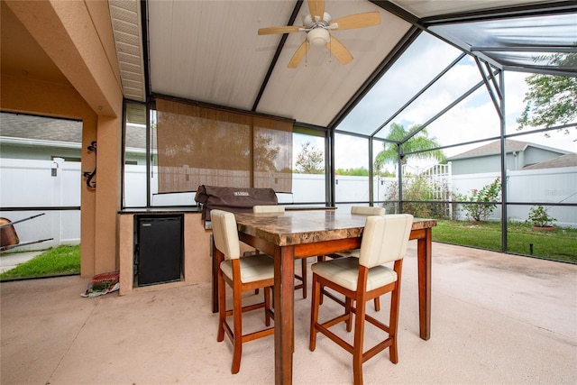 view of patio / terrace with outdoor dry bar, glass enclosure, exterior kitchen, and fence