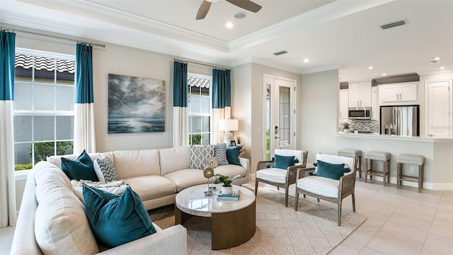 living room featuring light tile patterned flooring, visible vents, crown molding, and a ceiling fan