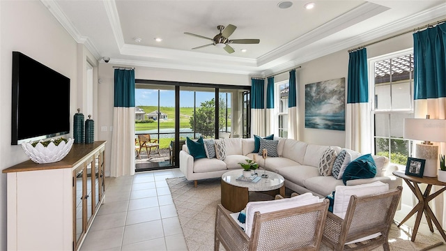 living area featuring a tray ceiling, ornamental molding, light tile patterned flooring, and ceiling fan