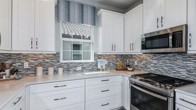 kitchen featuring tasteful backsplash, appliances with stainless steel finishes, white cabinets, and light countertops