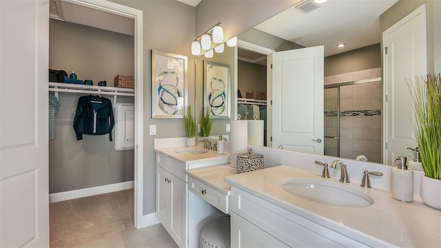 full bathroom with double vanity, a stall shower, a spacious closet, and a sink