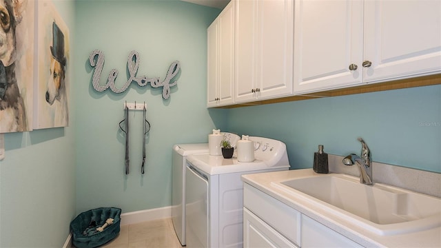 clothes washing area featuring tile patterned floors, a sink, cabinet space, separate washer and dryer, and baseboards