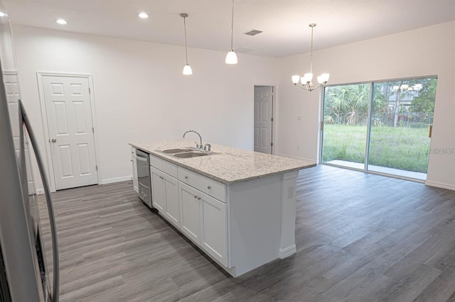 kitchen with a kitchen island with sink, a sink, stainless steel dishwasher, wood finished floors, and an inviting chandelier