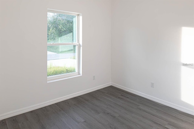 empty room featuring baseboards and dark wood-style flooring