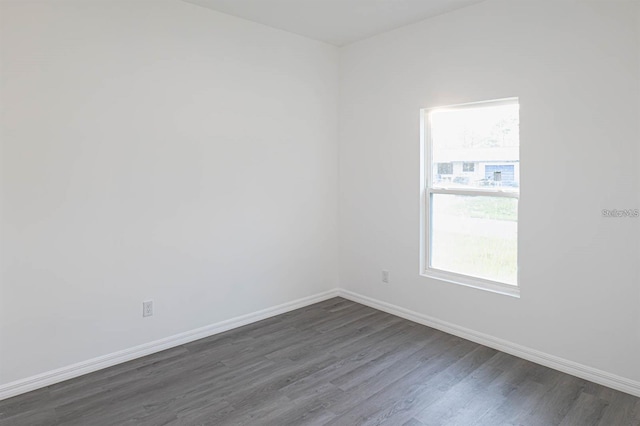 spare room with dark wood-style floors, plenty of natural light, and baseboards