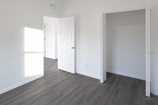 unfurnished bedroom featuring visible vents, baseboards, and dark wood-style flooring