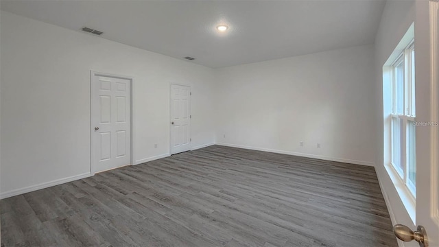 spare room featuring dark wood-type flooring, visible vents, and baseboards