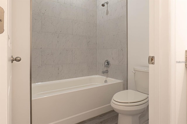 full bathroom with bathing tub / shower combination, toilet, and wood finished floors