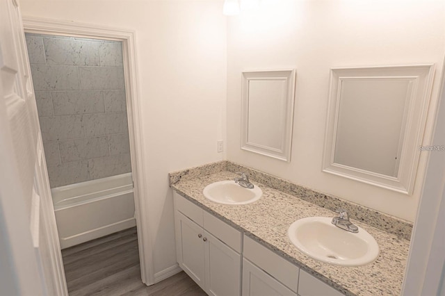 bathroom featuring double vanity, wood finished floors, shower / tub combo with curtain, and a sink