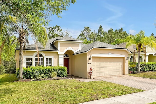 view of front of property featuring stucco siding, a front lawn, decorative driveway, a shingled roof, and a garage