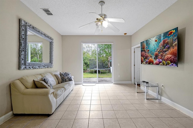 living room with light tile patterned floors, visible vents, a healthy amount of sunlight, and a ceiling fan