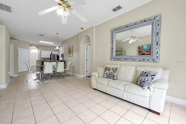 living room with arched walkways, visible vents, ceiling fan, and light tile patterned flooring