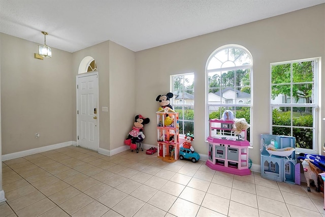 rec room featuring light tile patterned floors, baseboards, and a textured ceiling