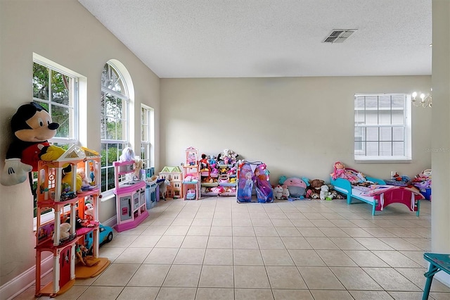 playroom with light tile patterned floors, visible vents, a notable chandelier, and a textured ceiling