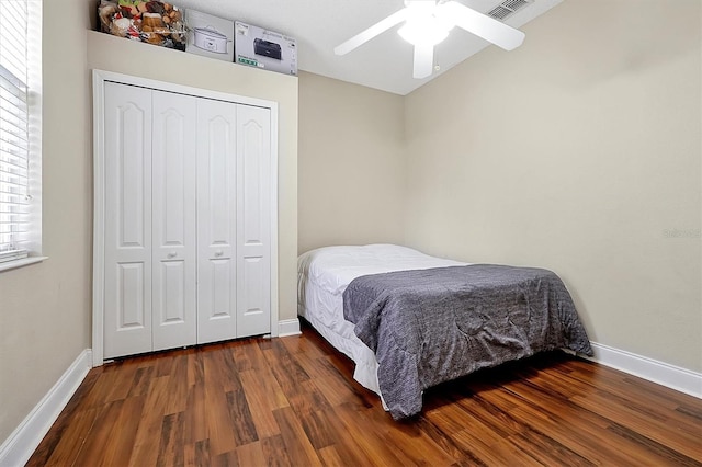 bedroom with a closet, visible vents, baseboards, and wood finished floors