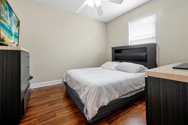 bedroom featuring ceiling fan, baseboards, and dark wood finished floors