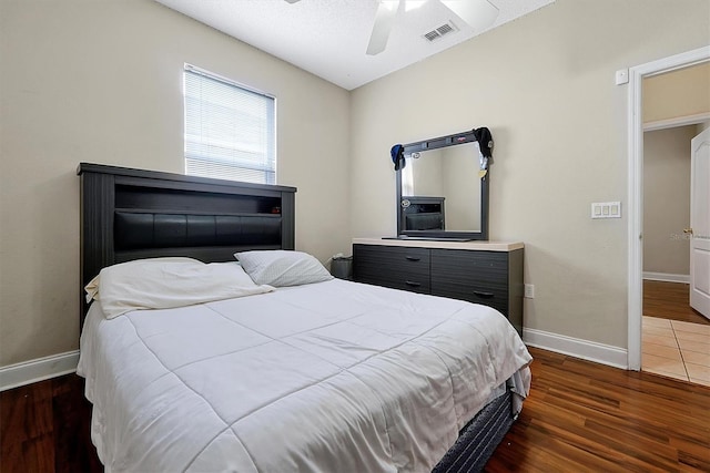 bedroom featuring visible vents, a ceiling fan, baseboards, and wood finished floors