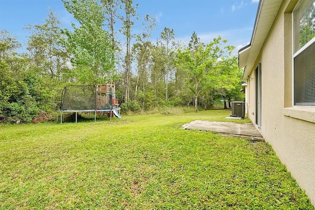 view of yard featuring a trampoline and central AC