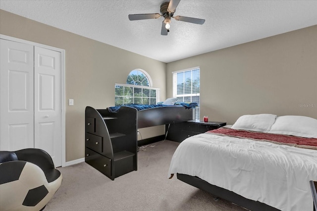 bedroom featuring a ceiling fan, light colored carpet, baseboards, and a textured ceiling