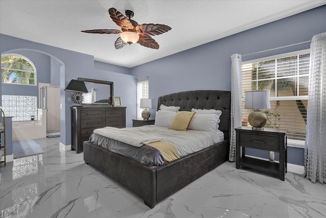 bedroom with baseboards, arched walkways, marble finish floor, and ceiling fan