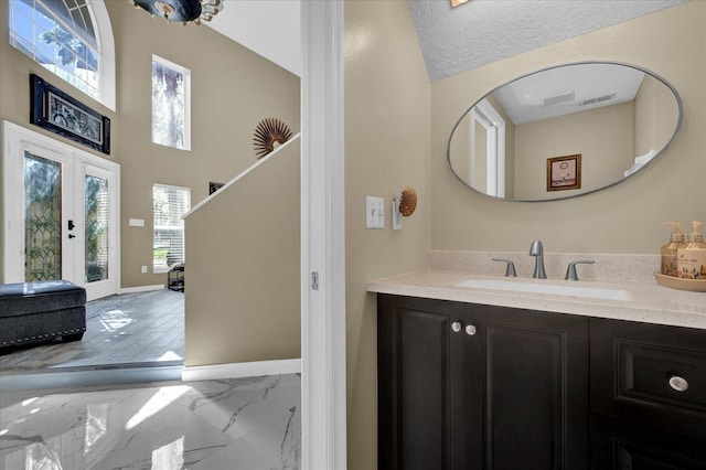 bathroom featuring vanity, baseboards, french doors, a textured ceiling, and marble finish floor