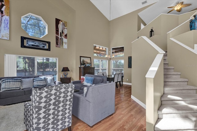 living room with visible vents, baseboards, light wood finished floors, stairs, and a notable chandelier