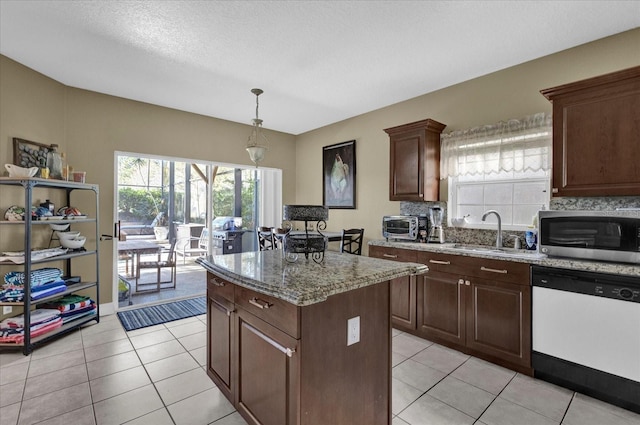 kitchen featuring light tile patterned floors, a sink, dishwasher, stainless steel microwave, and a center island