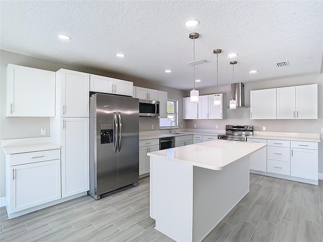 kitchen with visible vents, a sink, stainless steel appliances, white cabinets, and wall chimney exhaust hood