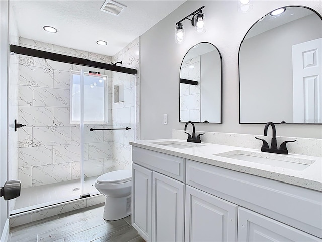 full bathroom featuring a sink, visible vents, toilet, and a shower stall