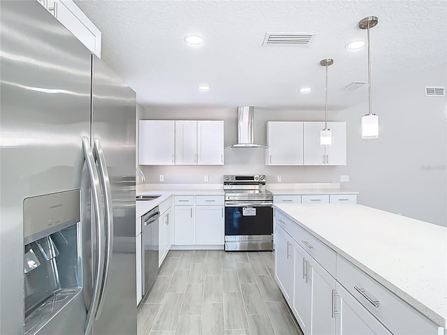 kitchen featuring visible vents, stainless steel appliances, wall chimney exhaust hood, and light countertops