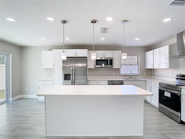 kitchen featuring visible vents, a center island, light countertops, appliances with stainless steel finishes, and a sink