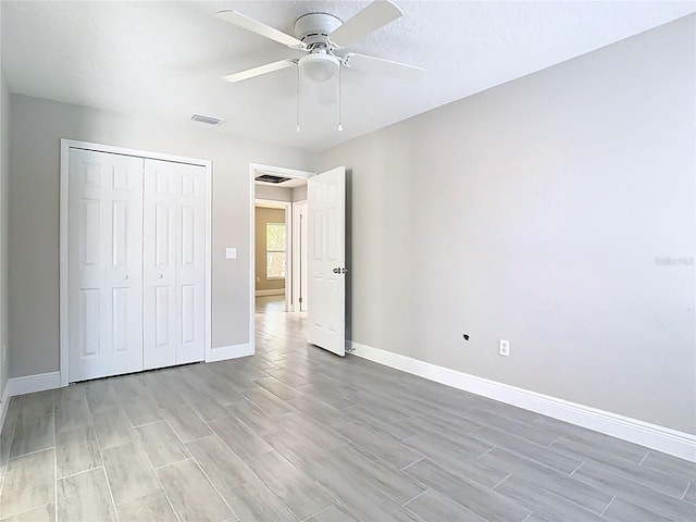 unfurnished bedroom featuring wood finish floors, visible vents, a ceiling fan, a closet, and baseboards