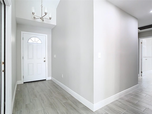 foyer with wood finish floors, baseboards, and an inviting chandelier