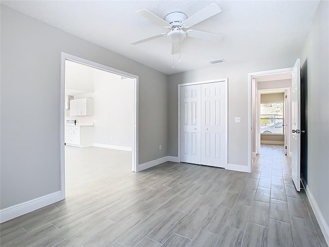 unfurnished bedroom featuring visible vents, a closet, baseboards, ceiling fan, and wood tiled floor