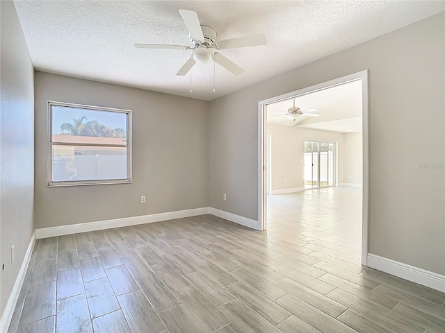 spare room featuring light wood-style flooring, a textured ceiling, baseboards, and a ceiling fan