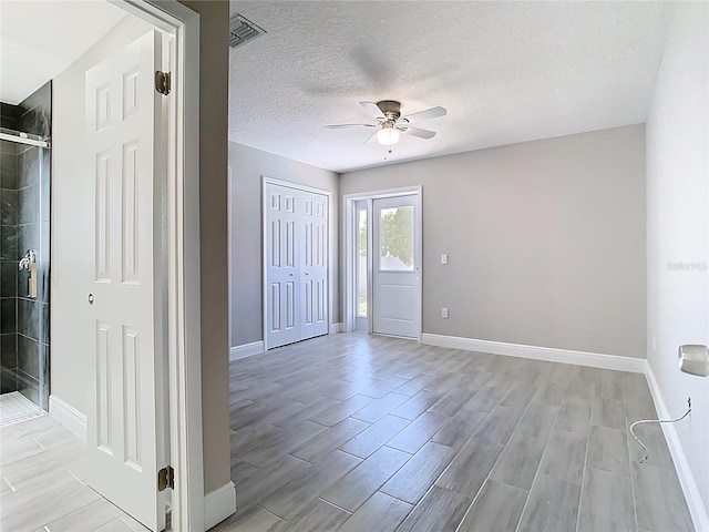 spare room with wood finish floors, visible vents, a ceiling fan, a textured ceiling, and baseboards