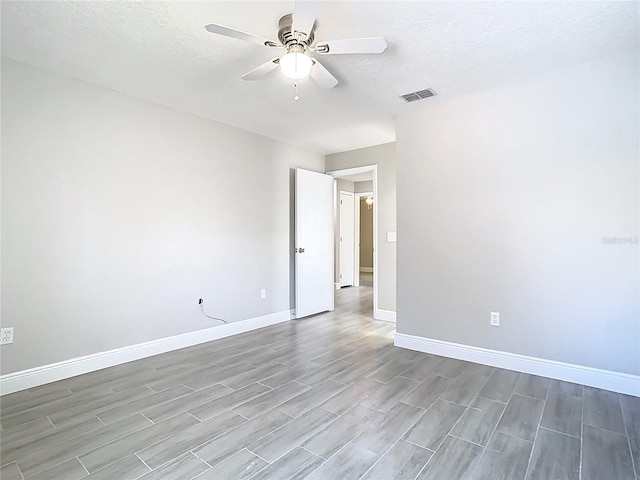 spare room with visible vents, baseboards, a textured ceiling, and ceiling fan