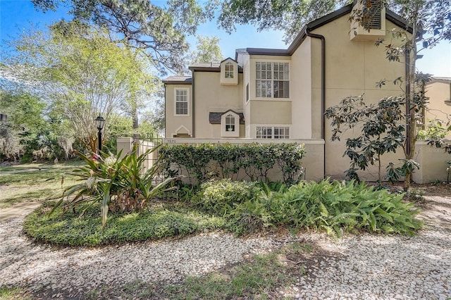 view of side of property featuring fence and stucco siding