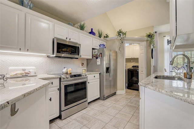 kitchen featuring backsplash, vaulted ceiling, stainless steel appliances, white cabinetry, and a sink