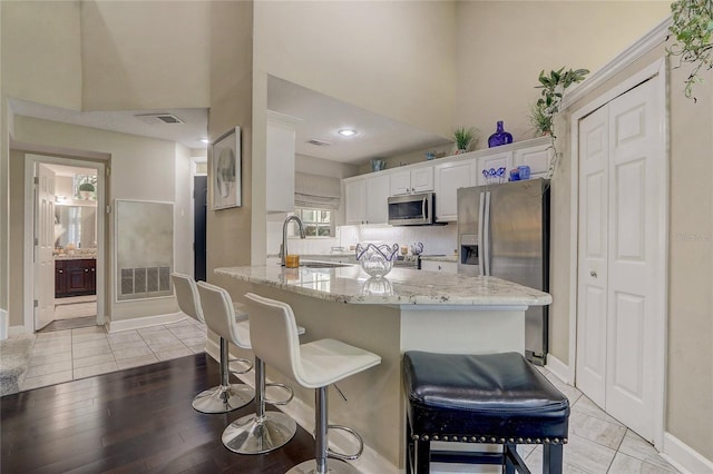 kitchen featuring visible vents, light stone countertops, stainless steel appliances, and a sink