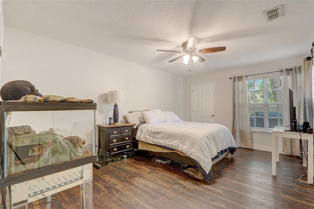 bedroom with visible vents, a textured ceiling, ceiling fan, and wood finished floors