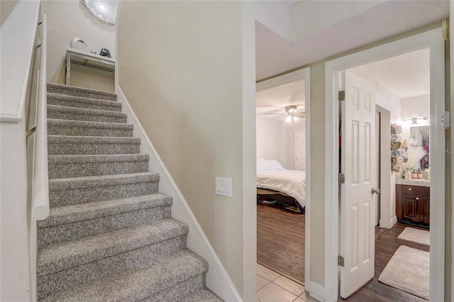 staircase featuring baseboards, ceiling fan, and wood finished floors