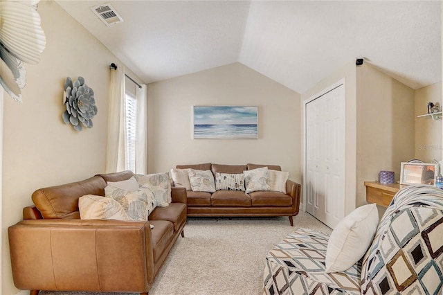 living area with vaulted ceiling, light colored carpet, and visible vents