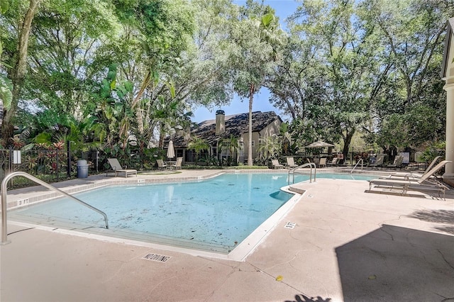 community pool with a patio and fence