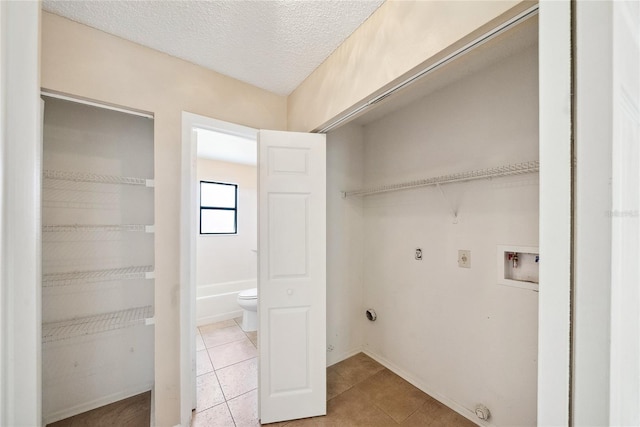 laundry area with hookup for a washing machine, light tile patterned floors, laundry area, electric dryer hookup, and a textured ceiling