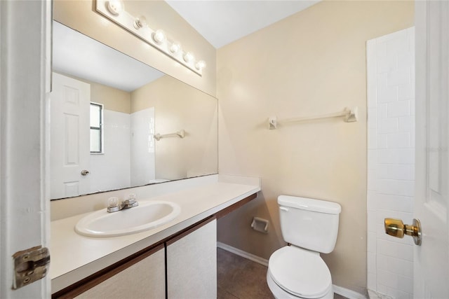 bathroom with toilet, vanity, and baseboards